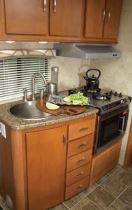 The round, stainless-steel sink in the galley is augmented by a high-rise, single-lever faucet; a pull-out sprayer; and a wooden sink cover.