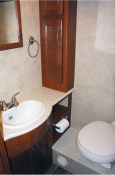 The street-side bathroom in the A.C.E. by Thor Motor Coach includes a raised toilet positioned atop a framed box.
