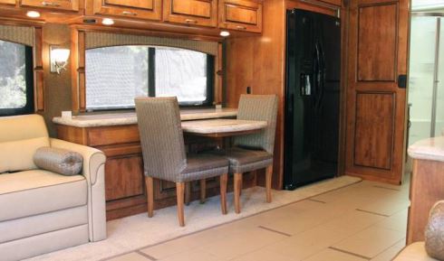 The front curbside slideout includes a pull-out dining table, with ample room for serving dishes on a shelf under the adjacent window.
