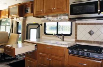The kitchen in the Thor Motor Coach Palazzo incorporates a three-burner high-output cooktop; a convection-microwave oven; a tile backsplash; and solid-surface countertops, including a pull-out extension.
