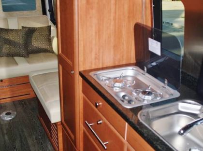 The two-burner, propane-powered cooktop and the single-basin sink in the galley are concealed by hinged covers when not in use.