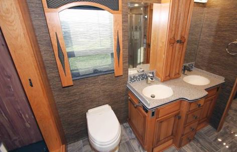 The rear bathroom contains a macerator-style porcelain toilet and a dual-basin vanity.