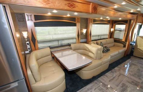The London Aire's full-wall street-side slideout runs from behind the cockpit back through the bedroom. The front portion houses an 84-inch sofa bed, a Euro booth dinette, and a residential refrigerator.
