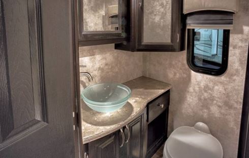 A window provides natural light in the bath area, and a vessel sink adds a luxurious touch.