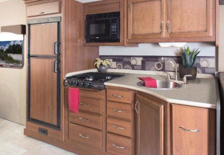 The fully equipped galley features a residential-size double-bowl sink, a three-burner range, a microwave oven, and a 6.6-cubic-foot refrigerator.