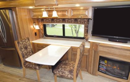 The front driver's-side slideout in this quad-slide motorhome holds a 20-cubic-foot residential refrigerator, a dinette, an entertainment center, and an optional fireplace.