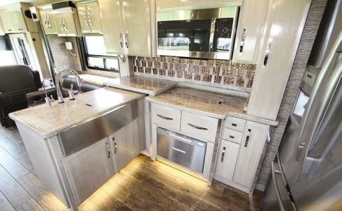 The fully equipped kitchen has a peninsula that houses the stainless-steel apron-front sink, which remains usable in part when the slideout retracts.