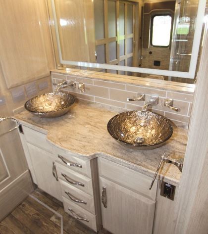 A frameless glass surround, as well as vessel sinks and high-end fixtures, adorn the bathroom.