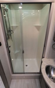 The bathroom features a glass-enclosed shower.