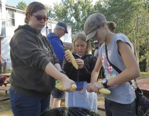 From left, Lindsay, Mary Emma, and Jennifer Davis shuck corn in Maine. 