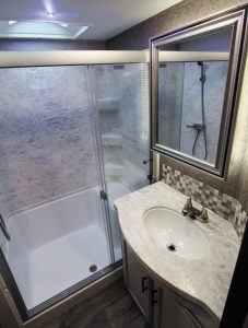 The bath in the Jayco Eagle includes a shower with a built-in seat, and a backlit medicine cabinet with a custom framed mirror.