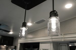 Decorative LED light bulbs and mason-jar-style globes hang over the galley island