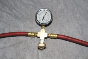 The tire inflator tool was made using inexpensive parts, including a glycerin-filled 200-psi pressure gauge, a brass quarter-turn drain valve, and hose connections.