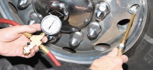 With an air hose plugged into his motorhome’s auxiliary air connection, the author fills a tire using the inflator tool he made. 