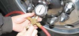 The author opens the tire inflator tool’s drain valve to lower the air tank pressure to a point where the gauge indicates the air compressor governor is kicking in. 