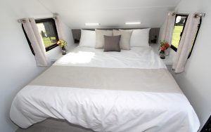 The front bedroom of the Travel Lite Evoke, with a curved ceiling, includes a 76-inch-by-80-inch king-size bed flanked by nightstands. 