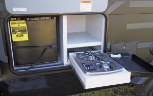 The exterior kitchen of the Travel Lite Evoke comes with a cooktop, a refrigerator, and storage.