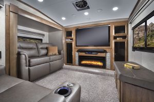In the 8297S floor plan, the living area is up front and contains a wall-length entertainment center with a 55-inch LCD TV and Bluetooth technology, among other features. Leather-look upholstery covers theater seating and a sofa bed.