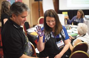 Richard Fritz assists a woman with a hands-on art project