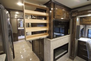 A pull-out pantry extends opposite the refrigerator, behind the center TV. 