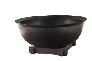 A basin used for boiling saltwater is displayed outside the cabin.