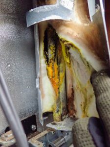 A strong ammonia odor and the presence of a yellow residue indicate an ammonia leak in the exposed tubing of a refrigerator cooling unit.