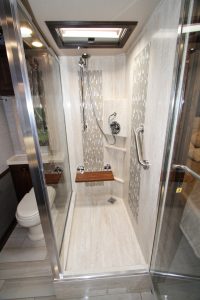The rear bath contains a tiled shower with a glass enclosure and a fold-down teak seat.