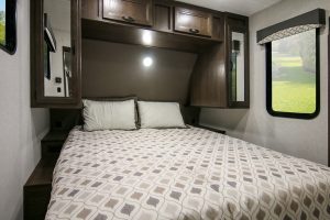 In the Winnebago Voyage 2427RB, the front master bedroom is encircled by storage cabinets, wardrobes, and nightstands.