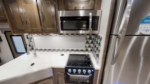 The galley features stainless-steel appliances, solid-surface countertops and covers, a shadowbox-style window, and a tile backsplash.