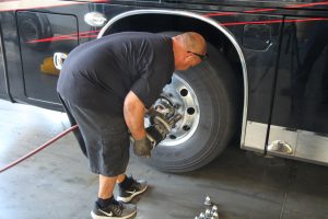 After lug nut covers and center trim caps are removed, the wheel is removed using a pneumatic impact wrench.