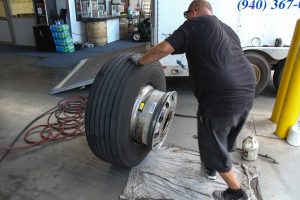 A tire is removed from the wheel using a tire iron.