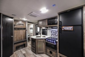 The 31BHDD’s main entry door is in front of the curbside galley, outfitted with a microwave oven and a three-burner propane cooktop.
