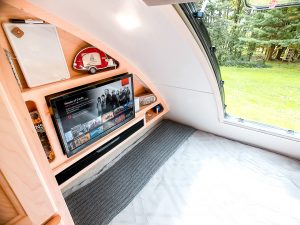 The rear bedroom includes a 24-inch TV with a sound bar, a queen-size mattress, and a “stargazing” window.