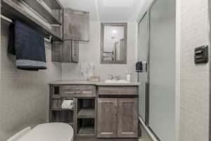 The bath includes cabinets, drawers, and storage cubbies; a 26-inch-by-38-inch molded shower; ample counter space around the vanity; and a marine-style toilet.