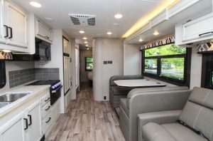 The Greyhawk 29MV sporting Modern Farmhouse décor. Its street-side slideout has a convertible dinette and a trifold sofa; the galley is opposite.