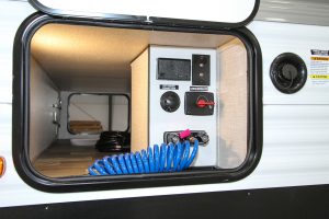 The RV includes an all-in-one location for the city water connection, battery disconnect, and hose sprayer.