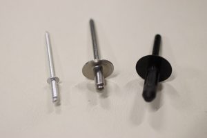 Blind hole rivets (left to right): aluminum, stainless steel with a large-diameter button flange, and black nylon.