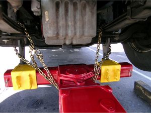 A motorhome built on a truck chassis with standard axles can be towed safely by lifting the I-beam axle, as shown here, and adding chains to secure the lift to the axle.