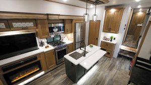 The Sanibel 3602 WB fifth-wheel offers open-concept living, with a 50-inch LED TV and a fireplace next to the galley.