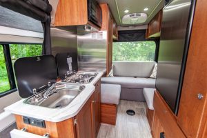 The galley includes a two-burner cooktop and a stainless-steel sink, both with covers.