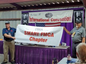 SMART FMCA’s banner is displayed by Paul Mitchell, International Area national vice president, left, and FMCA Military Veterans chapter president Bob Weithofer.