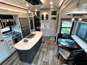 The galley features residential-size appliances, a large island, a movable dining table with extension, and designer lighting.