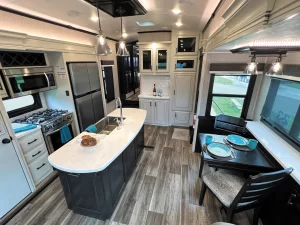 The galley features residential-size appliances, a large island, a movable dining table with extension, and designer lighting.