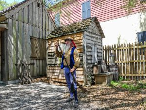 A docent in period dress demonstrates musket loading at the Colonial Quarter living history museum.