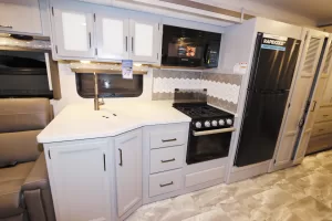 The galley features a solid-surface countertop and a decorative backsplash next to the three-burner cooktop.