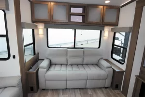 A sleeper sofa flanked by end tables rests against the RV’s rear wall.