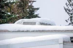 Carefully remove snow accumulation from an RV roof using a plastic-bladed roof snow rake.