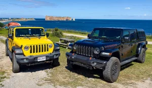 Jeeps owned by Wayne Brown and a friend are parked within sight of Percé Rock, which rises from the Gulf of St. Lawrence in Quebec, Canada. 
