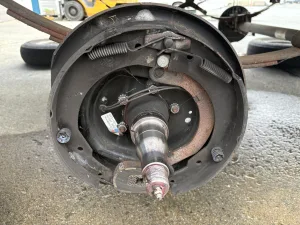 To pull off the brake drum, find the front nut; remove the cotter pin or spring; and take off the nut.
